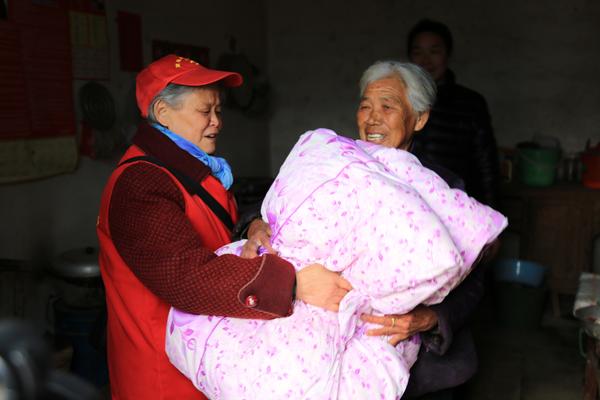 南召县爱心家园志愿者协会会长杜文兰为贫困家庭、孤寡老人送棉被。